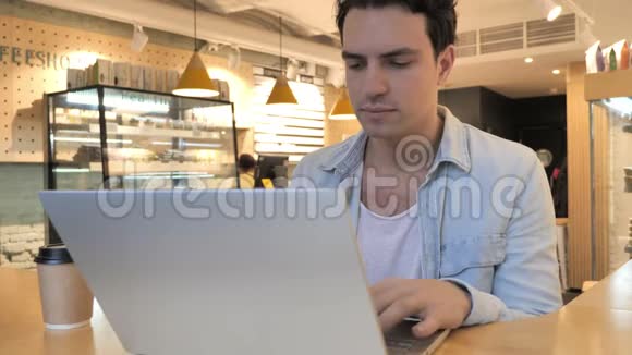 疲惫的年轻人在笔记本电脑咖啡厅工作颈部疼痛视频的预览图