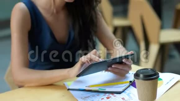 在咖啡馆工作年轻漂亮的长发女人坐在桌子旁在户外咖啡馆里使用平板电脑视频的预览图