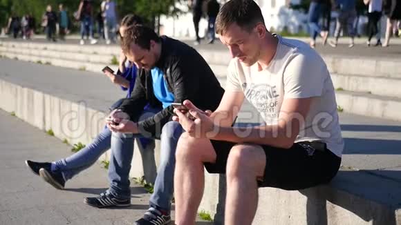 三个现代朋友在公园里交流坐在网上拿着手机下面的动作高清1920x1080视频的预览图