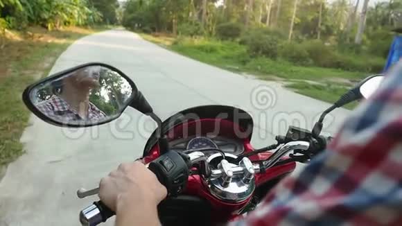 年轻的休闲男子旅行者驾驶摩托车在热带阳光明媚的道路上慢动作1920x1080视频的预览图