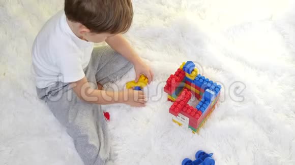 快乐的孩子在白色的背景下在地板上用彩色的积木玩耍子收集构造函数视频的预览图