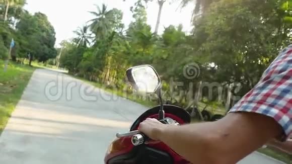 戴太阳镜的年轻人骑摩托车在热带阳光明媚的道路上慢动作快关门1920x1080视频的预览图