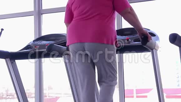 在跑步机上进行脂肪底层行走的女性在健身房进行积极的减肥锻炼视频的预览图