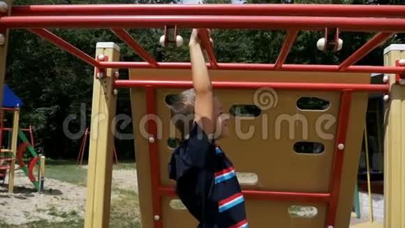小男孩用双手抓着猴子熊在户外运动场上慢动作地对抗天空锻炼视频的预览图