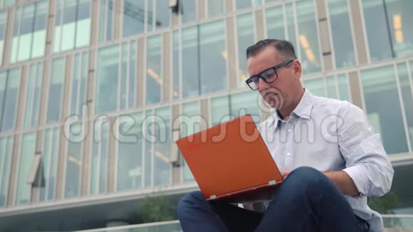 男人坐在楼梯上手提电脑视频的预览图