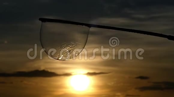 在灿烂的夕阳下肥皂泡在棍子上摇曳视频的预览图