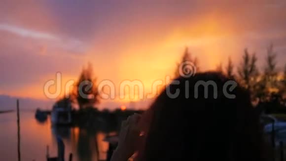 长发女孩在渔人码头用手机拍摄美丽的日落高清慢速运动泰国视频的预览图