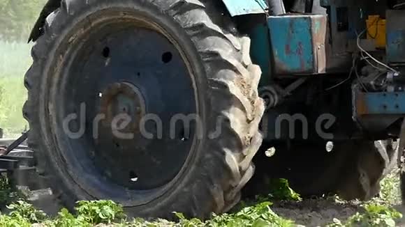 劳动拖拉机在夏天用绿色植物耕种田地视频的预览图
