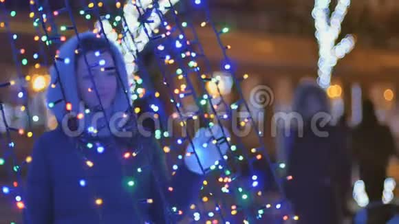 戴着围巾的漂亮女孩在圣诞节的明亮灯光下视频的预览图