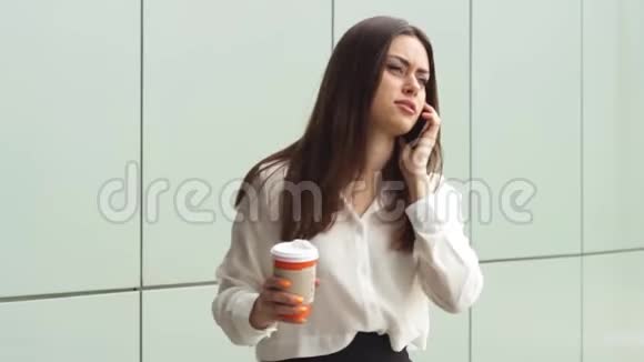 年轻女商人用智能手机喝热饮料视频的预览图