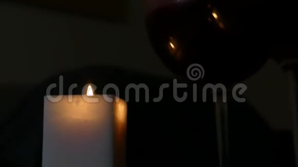 一支点燃的蜡烛和两杯酒在黑暗的房间里视频的预览图