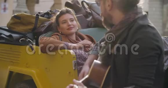 男人一边微笑一边和女朋友演奏吉他音乐女人听男朋友唱歌高加索夫妇视频的预览图