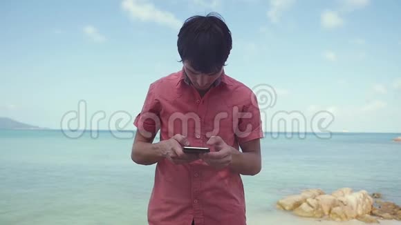 商人使用智能手机站在热带海滩附近慢动作1920x1080视频的预览图