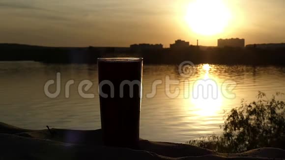 一个咖啡杯站在沙滩上的一个湖在美丽的日落缓慢的运动视频的预览图