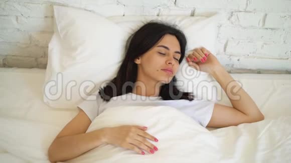 年轻迷人的女人躺在床上在家享受早晨女孩看着相机微笑视频的预览图