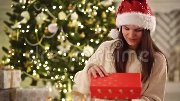 年轻快乐和情感的女孩在圣诞帽开幕魔术圣诞礼物红帽盒子里漂亮的女士视频的预览图