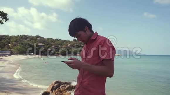 真正成功的人使用智能手机坐在热带海滩附近慢动作1920x1080视频的预览图
