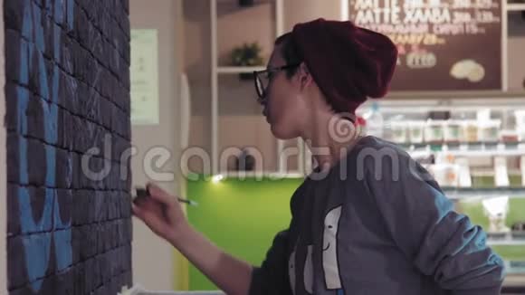 创意画家年轻的女画家用黑砖墙在咖啡店里转移平面设计视频的预览图