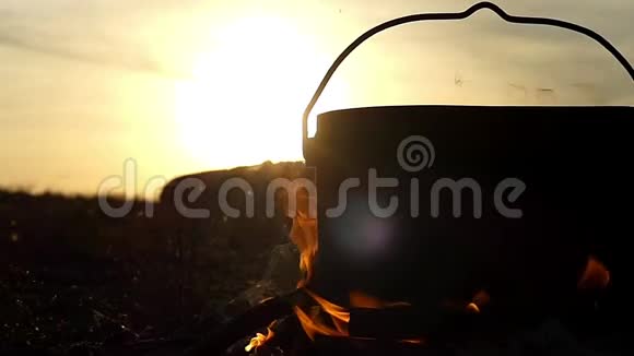 夕阳西下一个盛着水的大锅矗立在篝火中视频的预览图