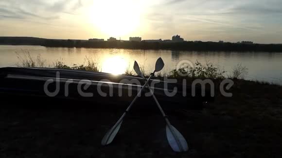 日落时分一艘双体船在湖岸上划桨视频的预览图