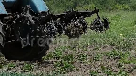 一辆带金属耙的蓝色拖拉机在夏末移动视频的预览图