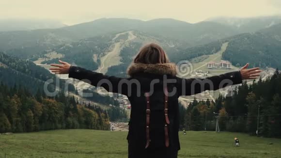 镜头跟随年轻女孩徒步旅行者在山上的风景举起手臂进入空中视频的预览图