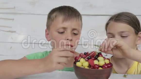 男孩吃樱桃和醋栗的新鲜浆果视频的预览图