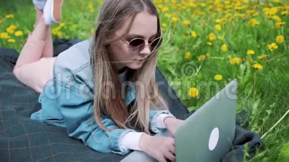 女孩躺在草地上用笔记本电脑工作视频的预览图