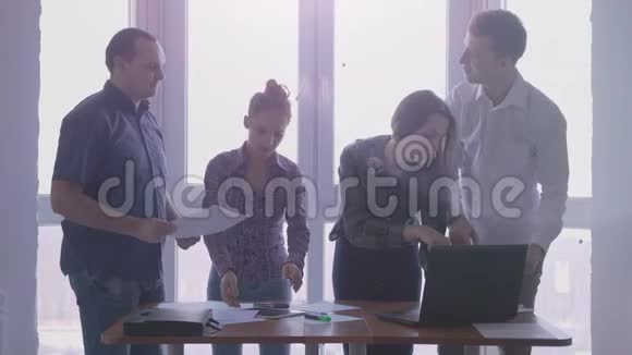 一群人在工作地点在一个时尚的办公室全景窗口英俊的年轻女子用触摸视频的预览图