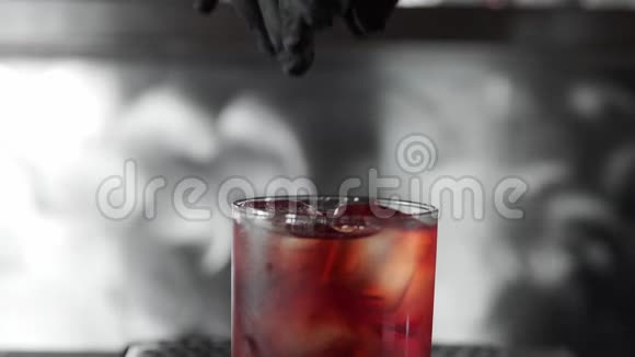 巴曼在Negroni鸡尾酒上挤压橙皮喷上橘皮放入杯中加入鸡尾酒视频的预览图