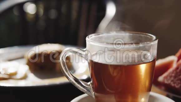 透明杯热红茶和早餐在木桌上模糊的背景上早晨的时间视频的预览图