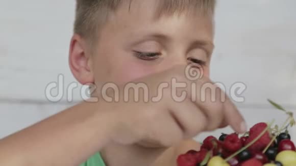 男孩吃樱桃和醋栗的新鲜浆果视频的预览图