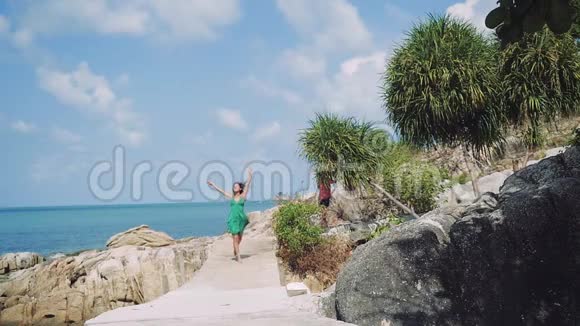 年轻迷人的黑发快乐的女人穿着绿色的长裙在海边奔跑兴奋和惊讶于大自然假日视频的预览图
