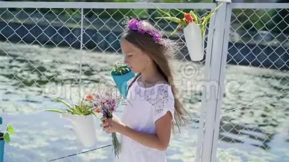 温柔的小女孩手里拿着花微笑着看着海湾酒吧的摄像机视频的预览图