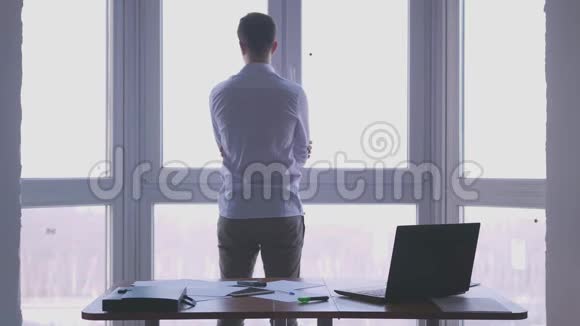 年轻的商人从窗口欣赏风景把他的手放在办公室里3840x2160视频的预览图