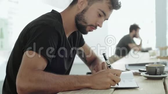 年轻人坐在咖啡馆里写计划视频的预览图