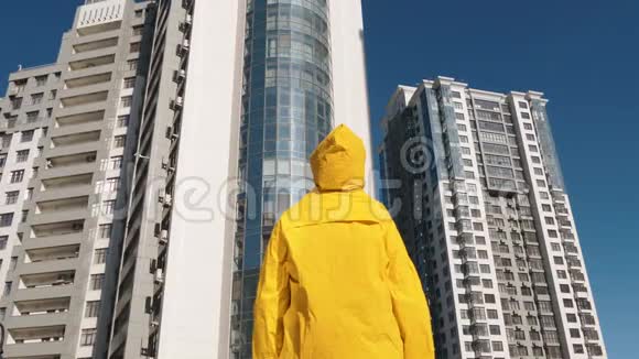 一个穿着黄色雨衣的人住在现代住宅区的前面视频的预览图
