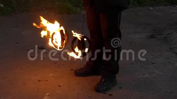 一个玩杂耍的人在秋天把两个点燃的火球缓慢地摆到户外视频的预览图