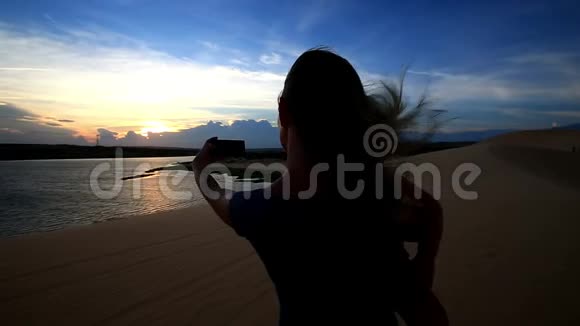 特写剪影母亲在日落时拍摄小女孩照片视频的预览图