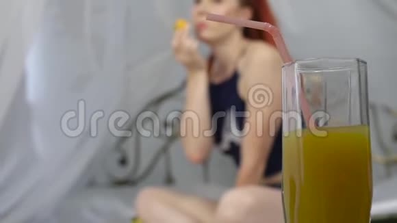 在床上享受的年轻女人用笔记本电脑和喝橙汁慢动作视频的预览图
