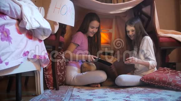 4在卧室里的自制房子里两个女孩用手电筒看书视频的预览图