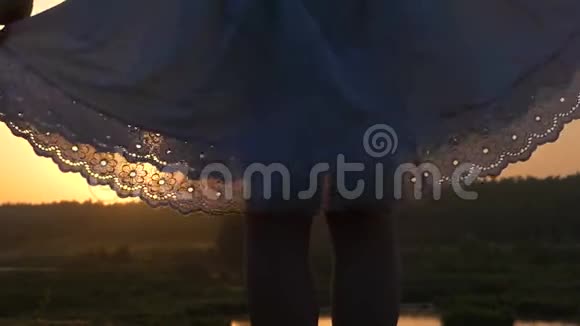 在斯隆莫的夕阳下年轻的女人用她白色的民间服饰的下摆嬉戏视频的预览图