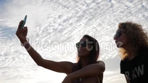 两个漂亮的白人女孩在智能手机上拍自拍生活方式HD慢速运动视频的预览图
