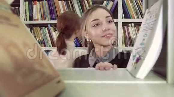 微笑女学生从书架上挑选合适的视频的预览图