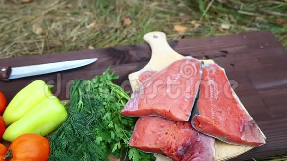 收获的蔬菜和红鱼在木切割板上用于木炭烹饪视频的预览图