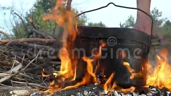 男人的手把刷子放在大锅下面放在邋遢的炉火上视频的预览图