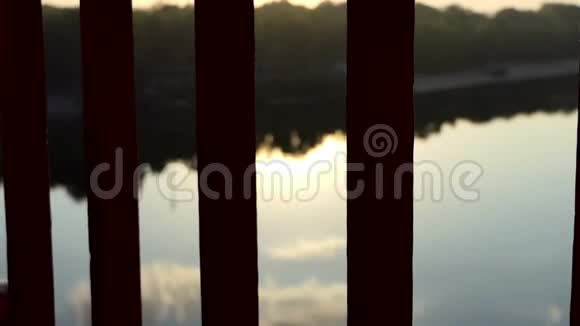 一个年轻人的手在日落的河桥上写些什么视频的预览图