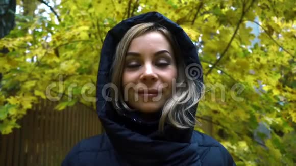 在秋天的大自然背景下把身穿黑色夹克衫头罩的年轻女子贴身贴身视频的预览图