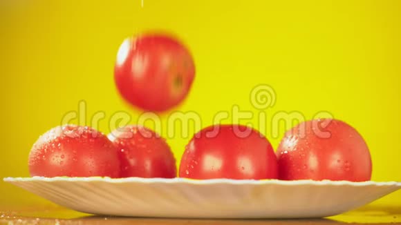 新鲜的西红柿掉在盘子里滴着水营养的概念在黄色背景下减速视频的预览图