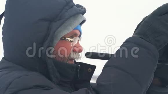 穿暖和衣服的老人在冬天在户外拍摄视频的预览图